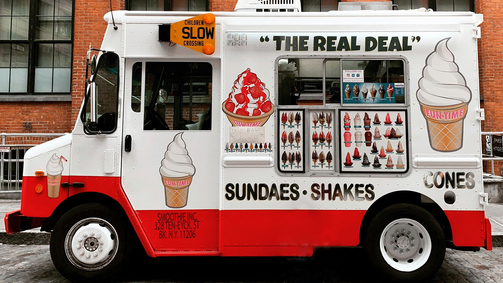 Un camion de glace blanc et rouge, décoré avec des cônes de glace, stationne dans une rue à New York.