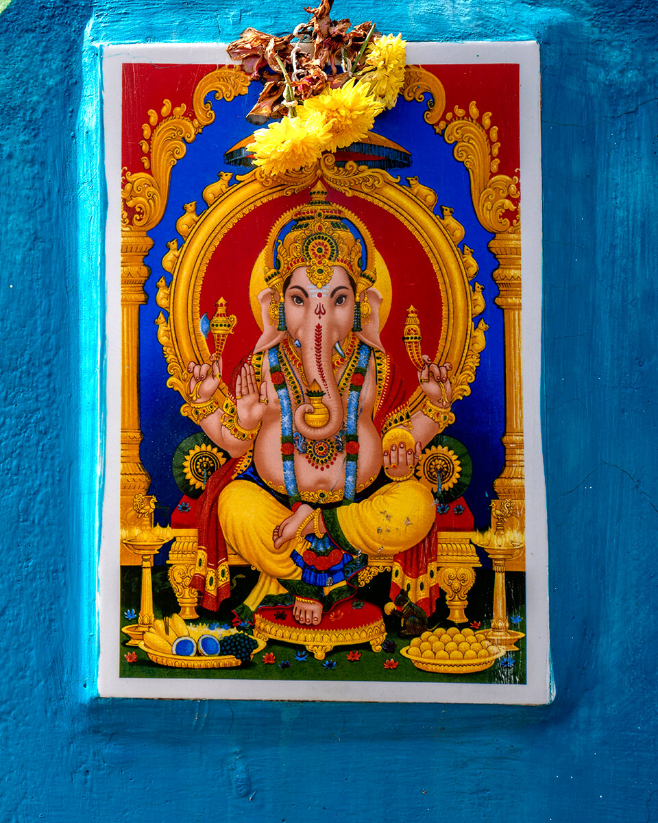 Cette photographie montre une peinture colorée à Pondichéry dans le quartier des pêcheurs, représentant Ganesh, le dieu hindou, en tailleur et orné de bijoux et de fleurs.