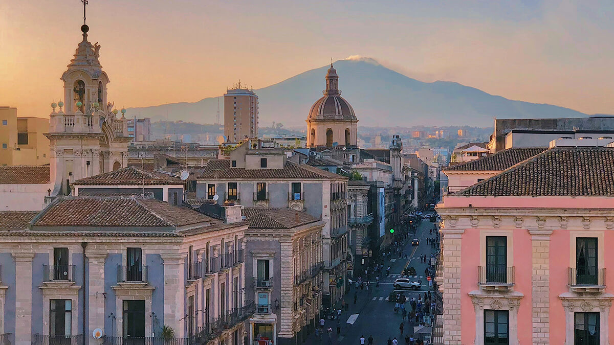 Vue de haut de la Via Etnea à la lumière de fin de journée, le volcan Etna en fond. 