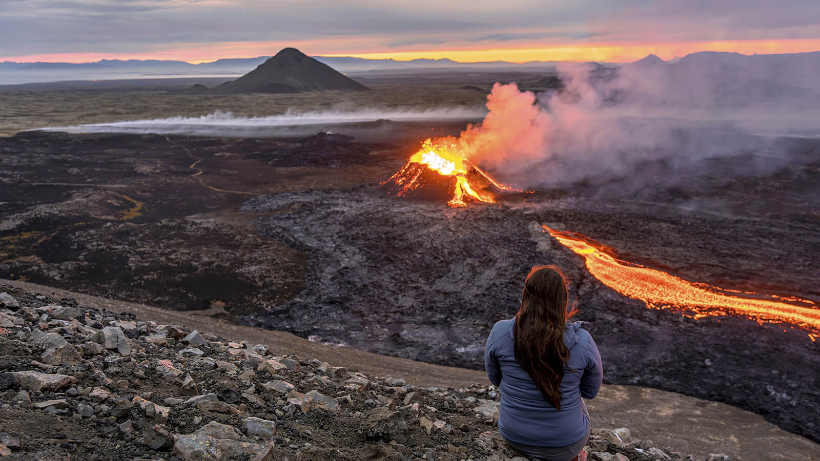 Photo d'une femme regardant une éruption d'un volcan dans les environs de Grindavík en Islande.