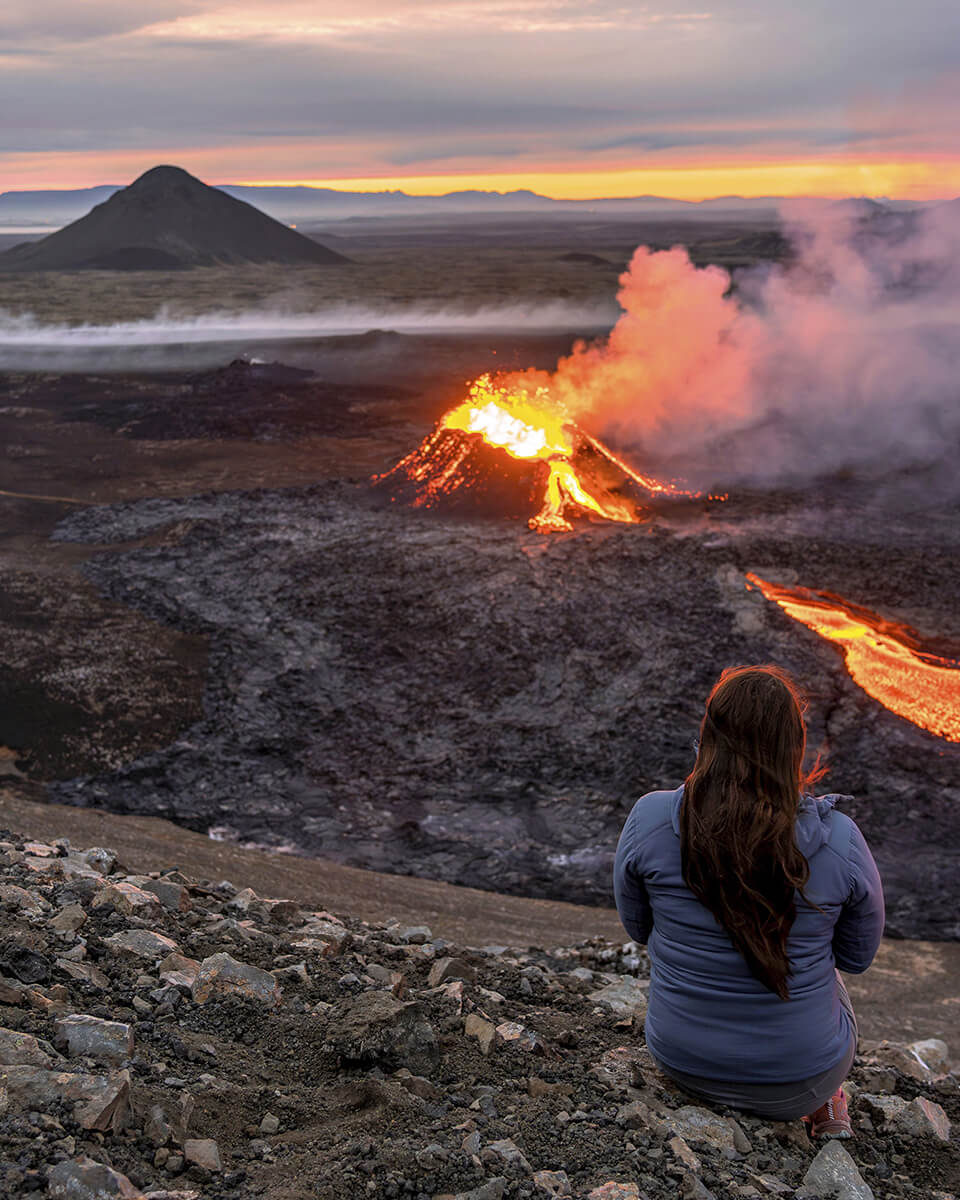Photo d'une femme regardant une éruption d'un volcan dans les environs de Grindavík en Islande.