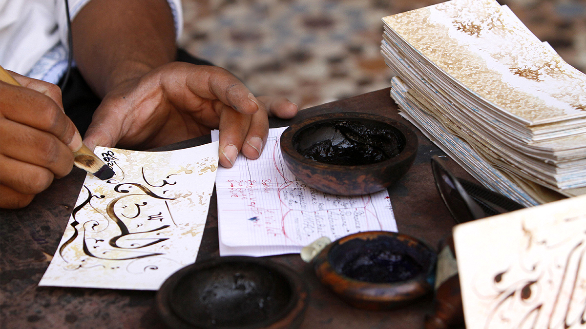Dans l'atelier du calligraphe Sadik Haddari. Il montre comment manier le calame biseauté.