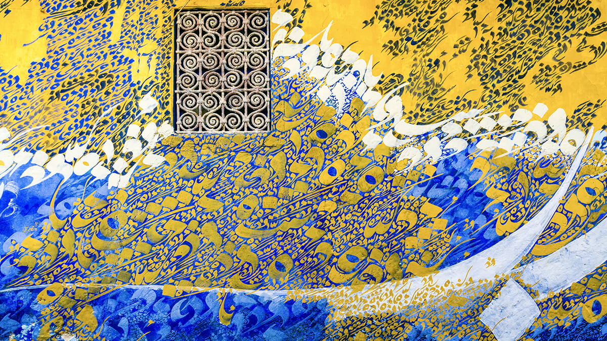 Une fresque murale de calligraphie arabe aux teintes contrastées de jaune, de bleu et de blanc avec des détails dorés.