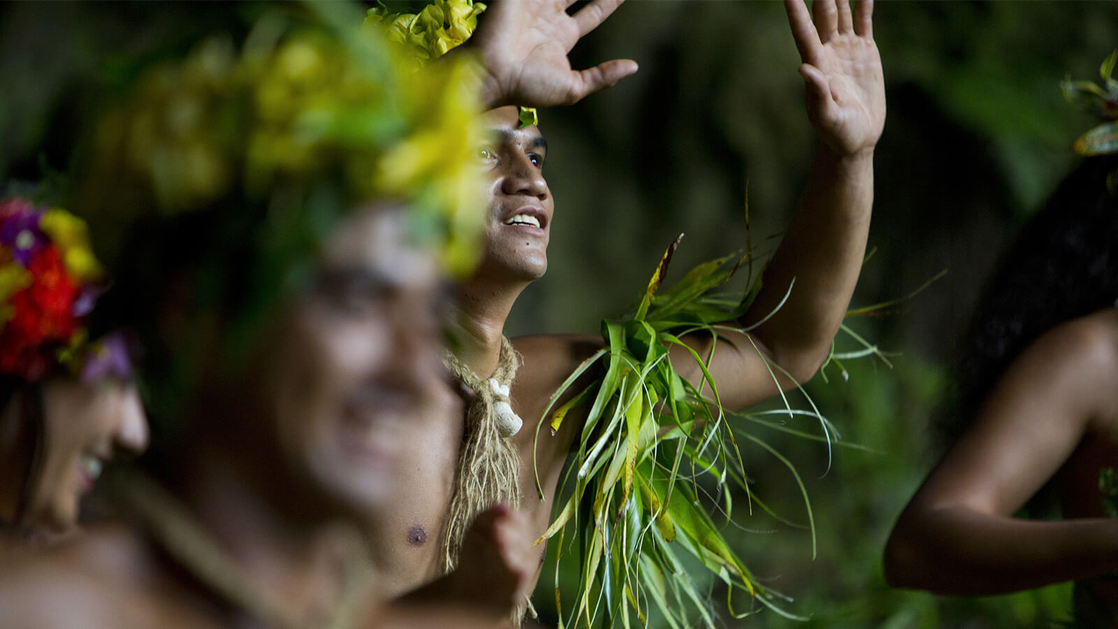 Des personnes participant au Heiva i Tahiti, vêtues de couronnes de fleurs et d'ornements végétaux en fibres naturelles.