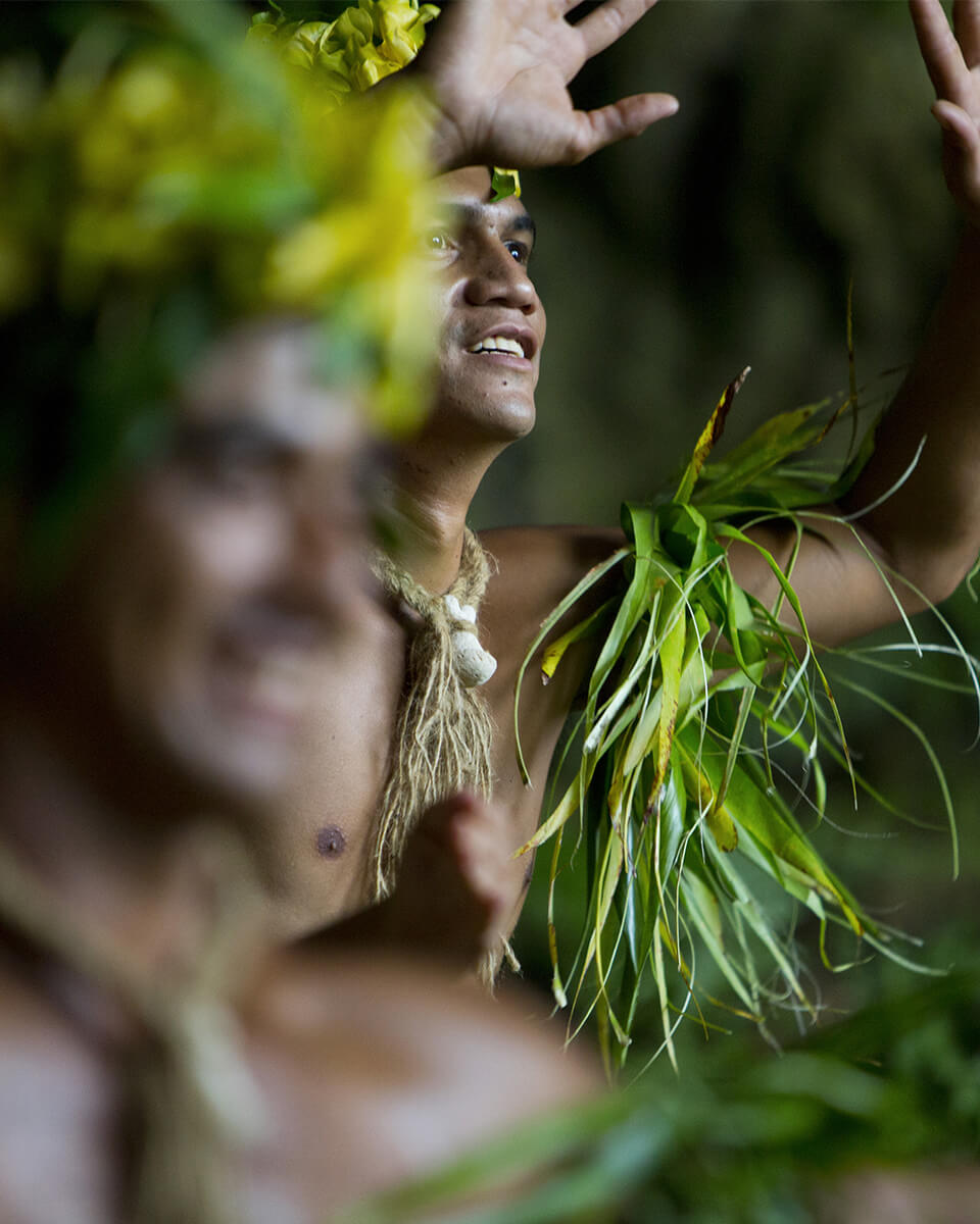 Des personnes participant au Heiva i Tahiti, vêtues de couronnes de fleurs et d'ornements végétaux en fibres naturelles.