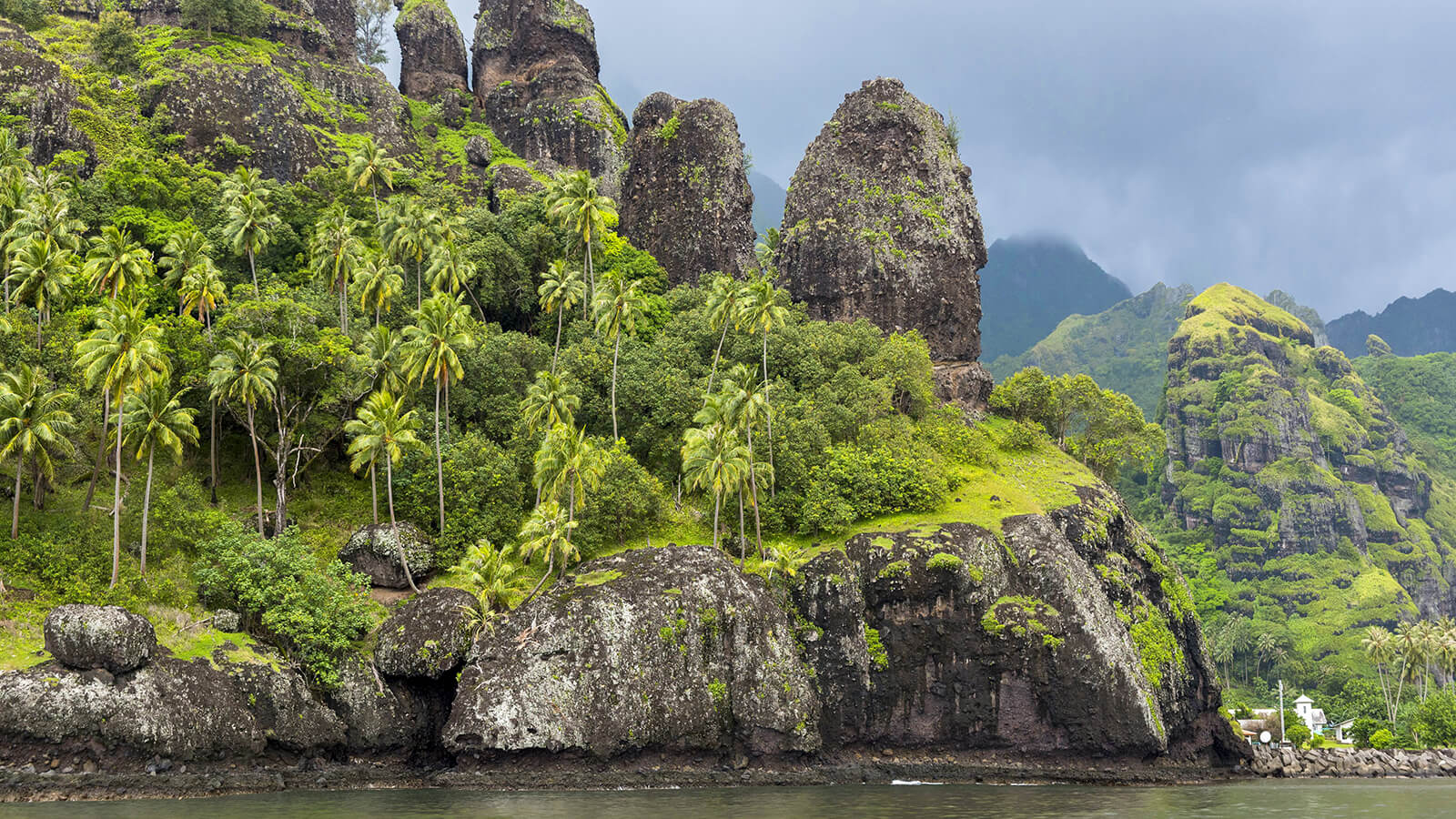 Photo de la baie de Hanavave, aussi appelée la baie des Vierges, sur l'île de Fatu Hiva aux Marquises en Polynésie française. On y voit les falaises volcaniques recouvertes de palmier et de végétation.