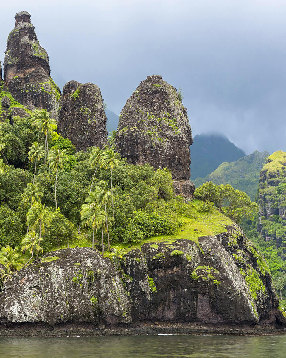 Photo de la baie de Hanavave, aussi appelée la baie des Vierges, sur l'île de Fatu Hiva aux Marquises en Polynésie française. On y voit les falaises volcaniques recouvertes de palmier et de végétation.